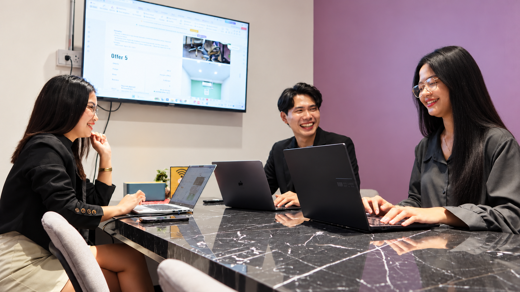 Enspace staff collaborating around a table with laptops in a meeting room.